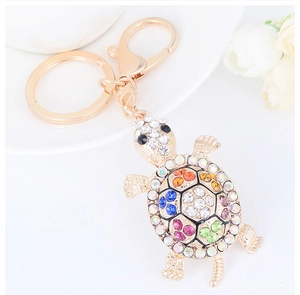 Close-up of a golden turtle keychain with multi-colored rhinestones and lobster clasp detail
