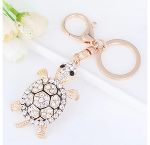 Detail of a sparkling rhinestone turtle keychain with polished golden alloy clasp and ring