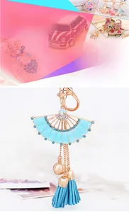 Détail d'un porte-clés éventail bleu clair avec strass, dorure et pompon en soie assorti