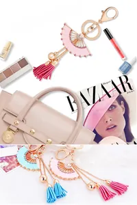 Détail du porte-clés en forme d'éventail rose avec accents dorés et pompon en daim