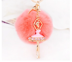 Close-up of pink fluffy fur ball keychain with golden ballet dancer and rhinestones