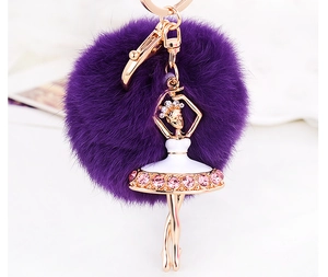 Detail of purple fluffy fur pompom keychain with gold ballerina dancer and pink crystals