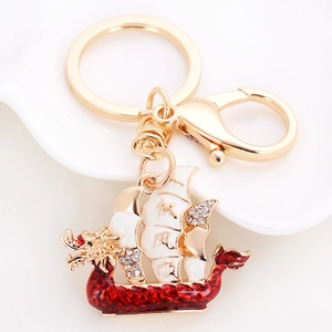 Detail of dragon boat keychain with red enamel and rhinestones on white background