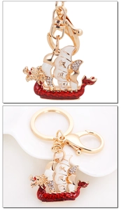 Detail of golden dragon boat keychain with red enamel coating and crystal sailboat
