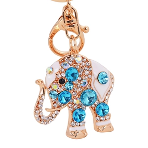 Porte-clés éléphant doré avec émail blanc et strass bleus sur un fond blanc neutre