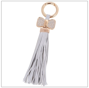 Detail of glitter bowknot and light gray leather tassel on rose gold keychain charm