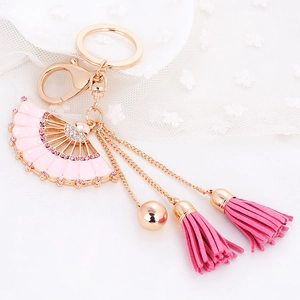 Porte-clés éventail doré avec émail rose, strass brillants et pompons en daim doux