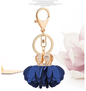 Detailed shot of dark blue fabric flower keychain with gold crown and sparkling rhinestones