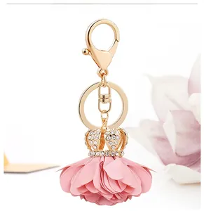 Close-up of golden crown pendant with rhinestones and pink fabric flower petals charm