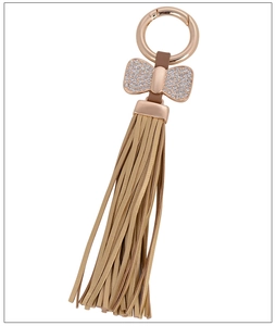 Detail of rose gold metal keychain with sparkling bow charm and golden leather tassel
