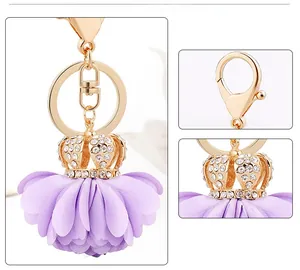 Detail view of golden lobster clasp and crown with purple fabric flower keychain