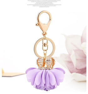 Detail of rhinestone crown and purple fabric flower charm on golden keychain