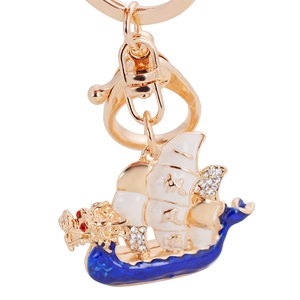Golden dragon boat keychain with white sails and sparkling rhinestones on white background