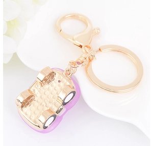 Vue détaillée d'un porte-clés voiture violet avec strass sur une assiette blanche