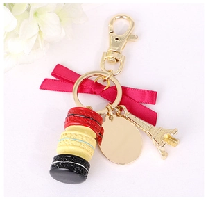 Close-up of macaron charms with silk bow and Eiffel Tower pendant on golden keychain