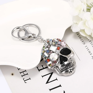 Detail of silver skull keychain with colorful rhinestones on a decorative tray