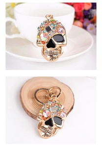 Detailed macro view of gold-tone skull keychain with colorful rhinestones and enamel accents