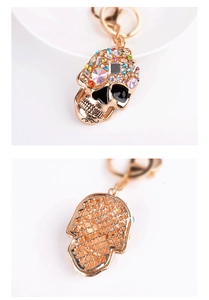 Front and back detail of a gold skull keychain with colorful rhinestones and floral hollow cut