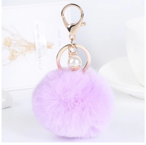 Detail of light purple fluffy keychain with pearl accent and golden metal ring fastener