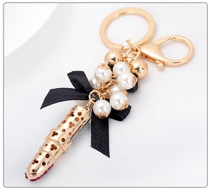 Détail du porte-clés rouge à lèvres avec perles blanches et ruban de nœud noir élégant