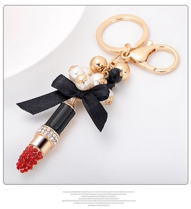 Détail du porte-clés rouge à lèvres avec strass rouges, nœud en soie et perles blanches