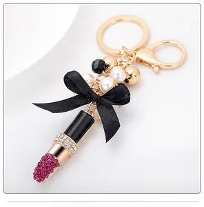 Détail d'un porte-clés rouge à lèvres élégant avec strass roses et perles blanches