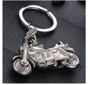 Polished silver metal motorcycle keychain with detailed wheels and engine on black background