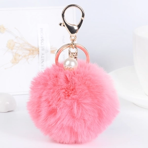 Pink faux fur pompom keychain with white pearl and gold clasp on white background
