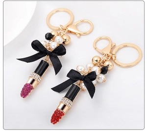 Détail d'un porte-clés rouge à lèvres avec strass, perles et élégant nœud noir