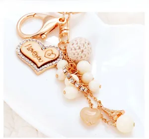 Dettaglio del cuore in legno con incisione I love you e perle su portachiavi d'oro chic