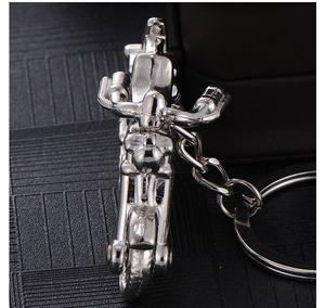 Close-up of a silver motorcycle keychain with realistic mechanical alloy structure