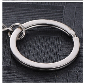 Close-up of polished silver metal key ring with flat double-loop design on black grid