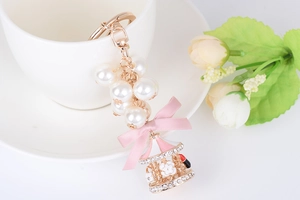 Detail of rose gold carousel keychain with pearls, pink bow and rhinestone camellia flower
