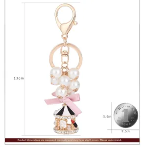 Detalle del llavero carrusel con perlas y lazo rosa mostrando la longitud de 13cm