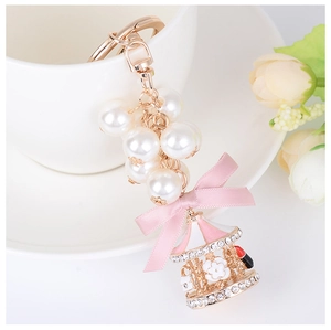Close-up of carousel charm keychain with pearls and pink ribbon on a ceramic cup