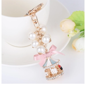 Detail of carousel keychain with cream pearls, pink ribbon bow and sparkling rhinestones