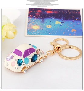 Detail of beetle car keychain with blue and purple rhinestones and golden ring clasp