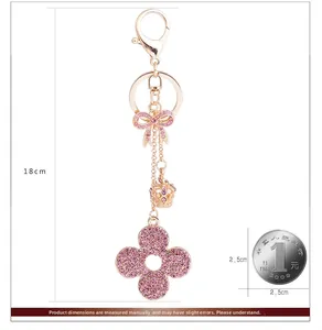 Detail view of 18cm four-leaf clover keychain with rhinestones and size comparison coin