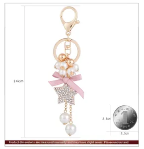 Detail of beaded bow keychain with pink silk ribbon, pearls and star pendant showing 14cm size
