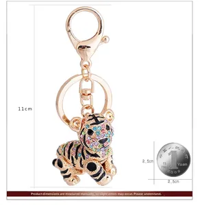 Detailed tiger keychain with colorful rhinestones next to a coin for scale reference