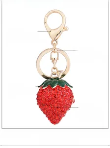 Detailed view of alloy strawberry keychain with red rhinestones and polished gold lobster clasp