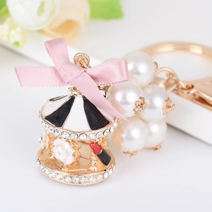 Exquisite carousel keychain with pearl accents and pink ribbon bow in golden finish