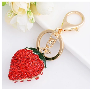 Macro shot of red rhinestone strawberry keychain with gold lobster clasp and green leaf