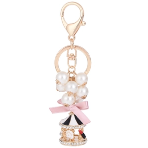 Golden carousel keychain with white pearls and pink silk bow on a white background