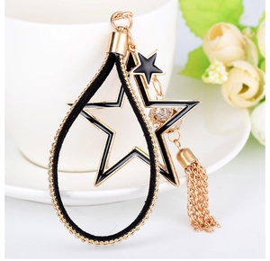 Dettaglio charm borsa a stella in smalto nero con strass e nappe metalliche dorate