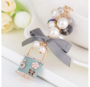 Détail d'un charme cadenas vert menthe avec perles et décor de nœud élégant