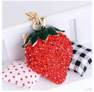 Close-up of strawberry keychain with red rhinestones and green enamel leaf detail