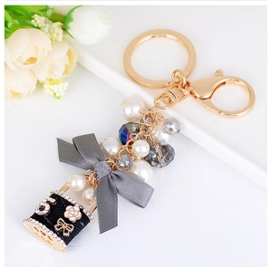 Détail du pendentif flacon de parfum avec chaîne de perles et nœud en satin gris doré