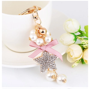 Detail of pink bow and rhinestone star pendant with white pearls on a gold keychain