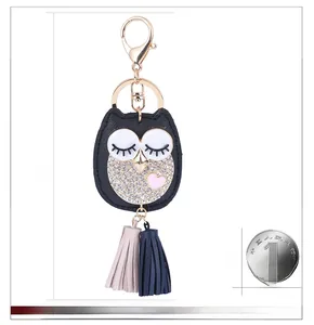 Détail du porte-clés chouette en cuir avec strass et pompons à côté de l'échelle de mesure